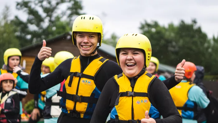 A group of smiling people wearing helmets and life vests