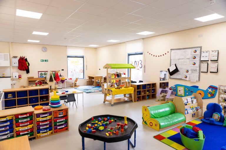 A colourful bright room in a nursery with lots of toys and furniture for children