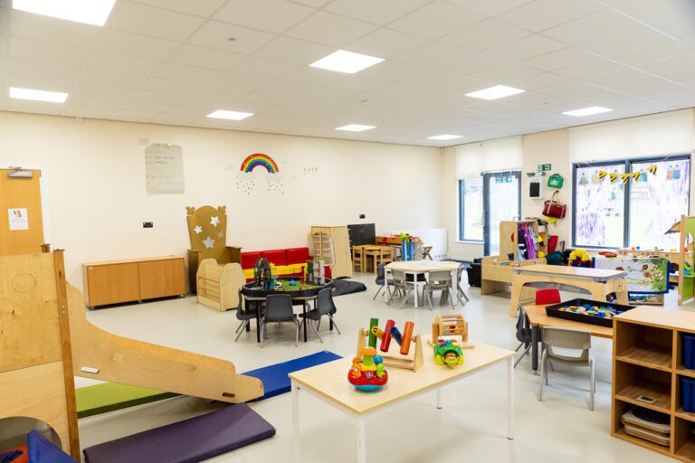 A colourful bright room in a nursery with lots of toys and furniture for children