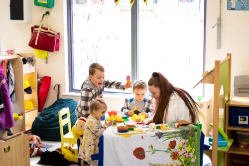 A woman and three children are doing crafts