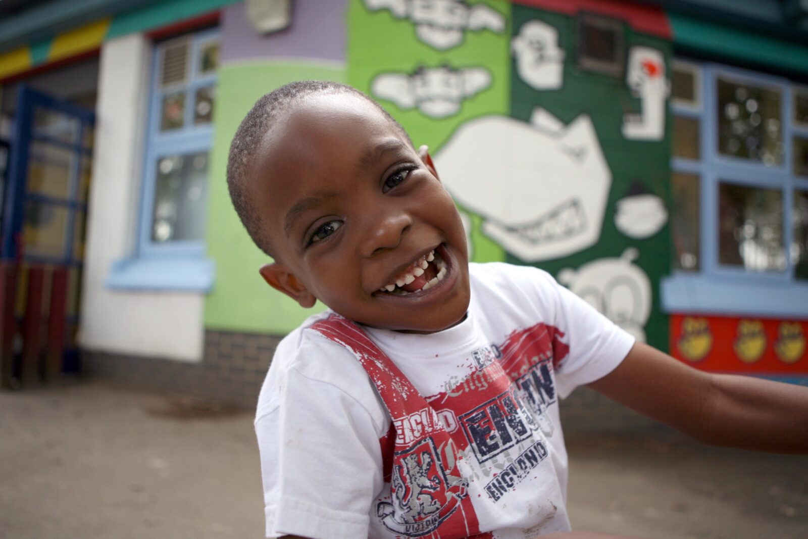 A young boy smiles while standing in front of a colourful building