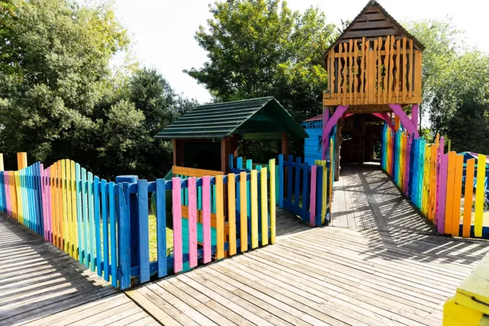 A photo of the bridge at Hackney Playground. There is fence all around it which was painted all the colours of the rainbow.