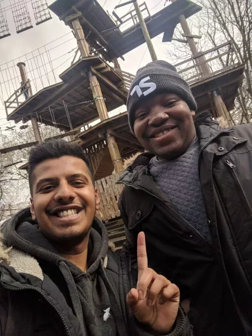 Dan and a staff member are photographed in front of a Go Ape contraption. The staff member is pointing up at Dan.