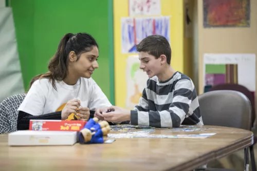 A staff member and a child are making a puzzle together.