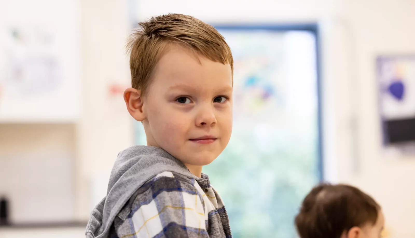 Photo of a boy's profile. His head is turned slightly to face the camera.