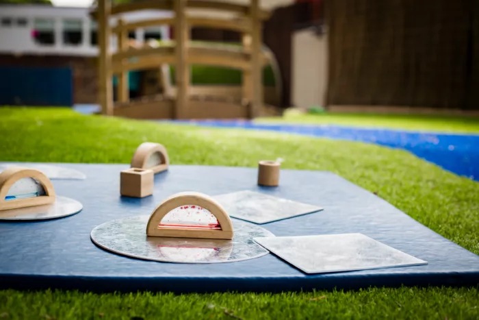 There is a blue mat on the grass with sensory items sitting on top.