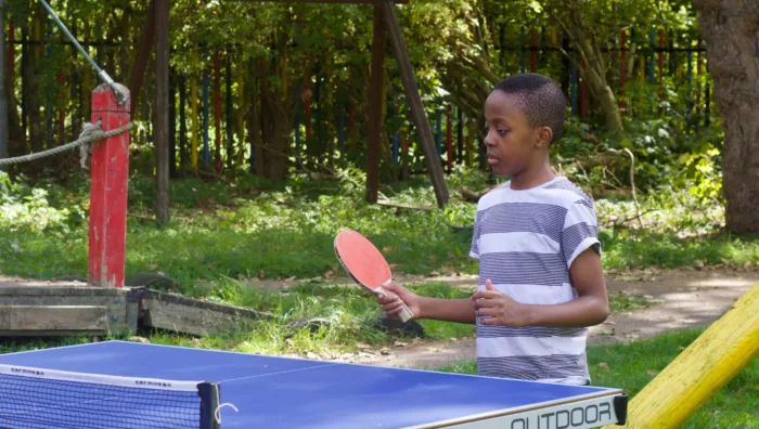 A boy plays table tennis outdoors