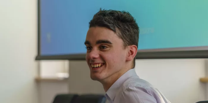 A young man in a smart shirt smiles