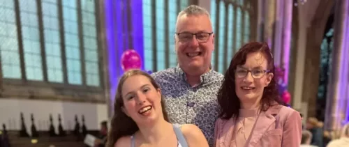 Asher and her parents are photographed together. They are at an event.