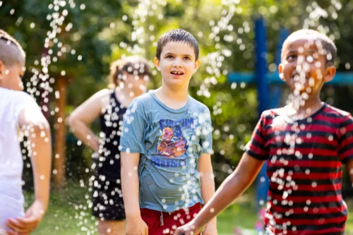 Children play outside on a sunny day with water drops raining down on them