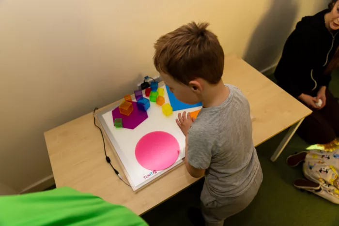 A child is photographed from behind, playing with sensory toys on a table.