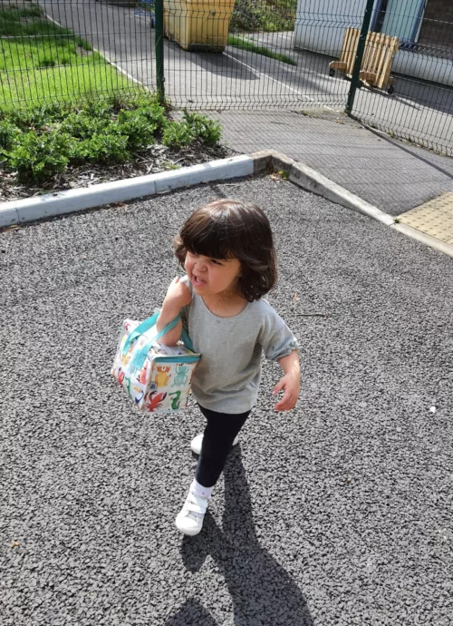A child walking while holding a lunch bag.