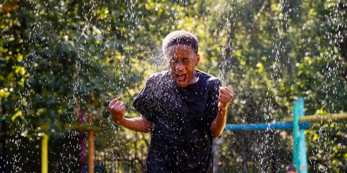 A boy laughing in artificial rain