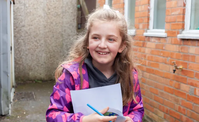 A girl holding a pen and paper in her arms