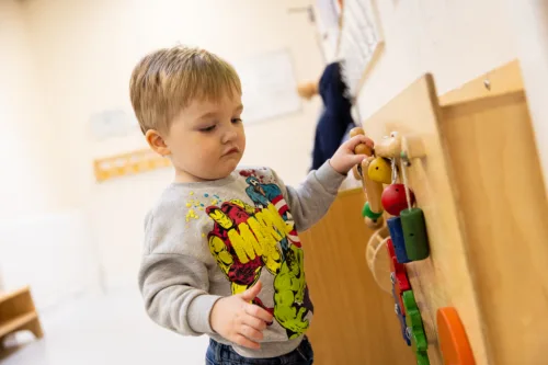 A boy is playing with toys on an activity wall