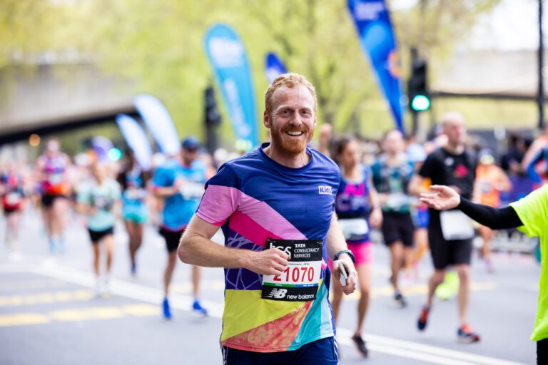 A man is running. He is wearing a Kids vest