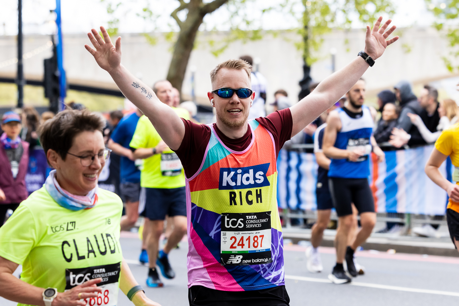 a man is running with his hands up in the air. He is wearing a Kids vest