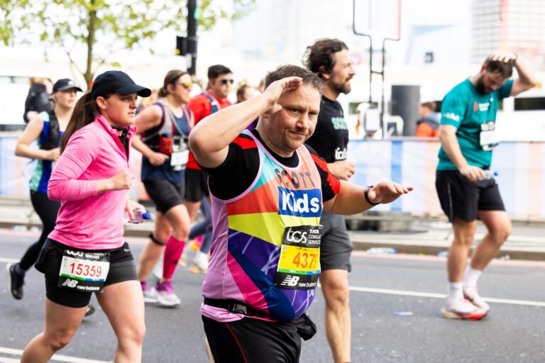 A man is running in a Kids vest. 