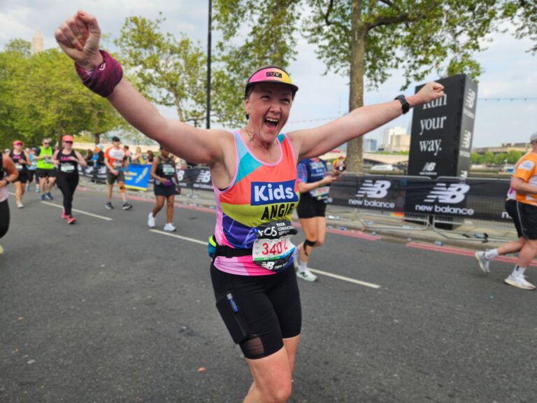 woman running london marathon cheering with her hands in the air
