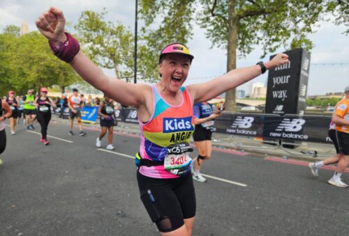 woman running london marathon cheering with her hands in the air