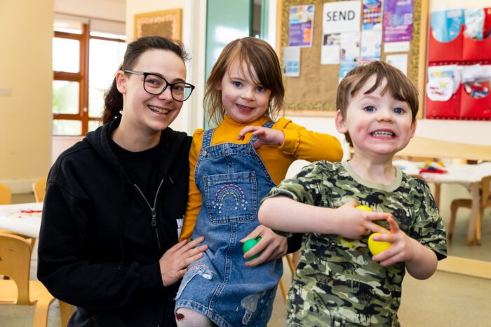 mum and two children smiling in a nursery