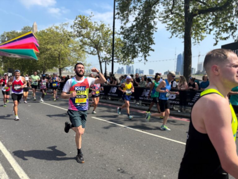 man running the london marathon waving his arm in the air
