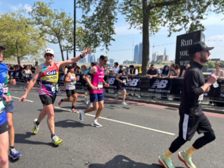 man running the london marathon waving his arms in the air