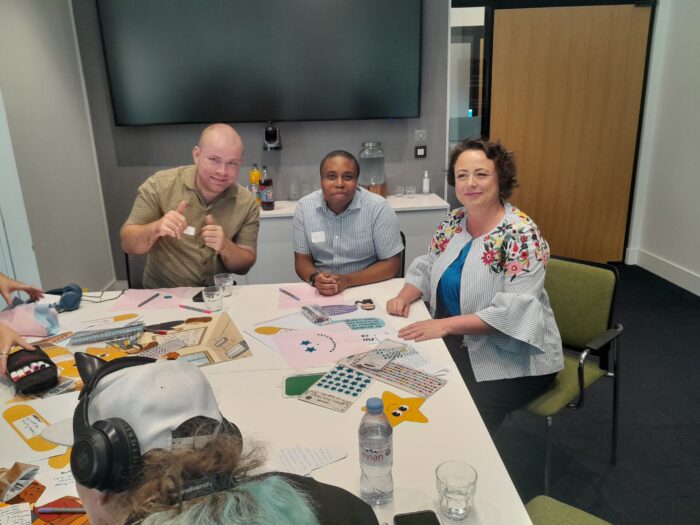 3 people are sitting and smiling; 2 are young boys and the other is a woman, Catherine Mckinnell, minister of schools