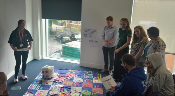 a group of young people are chatting whilst playing a game of giant snakes and ladders