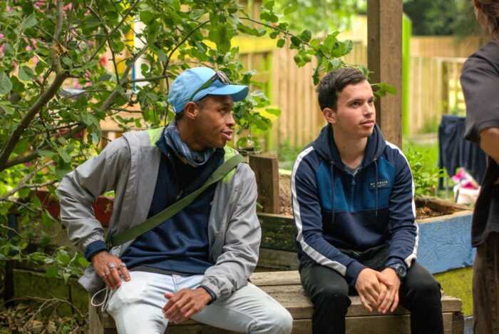 two teenage boys sitting on a bench next to each other