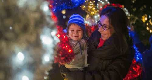 woman holding child in front a christmas tree