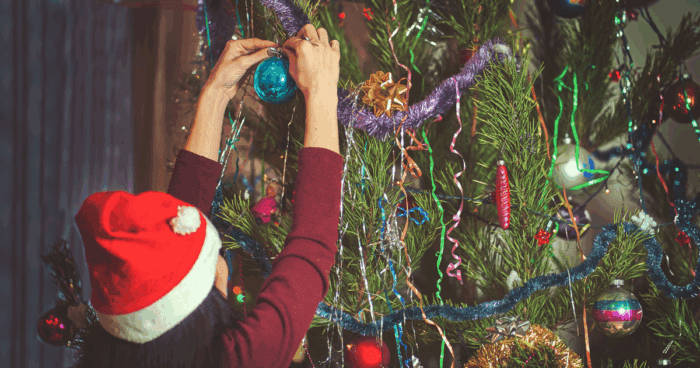 Teenager hanging a bauble on a christmas tree