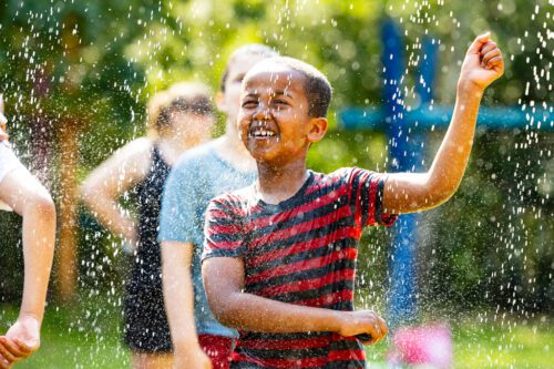 Young boy playing in a park with water sprinkler