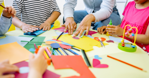 a group of children crafting on a table with coloured paper and pens