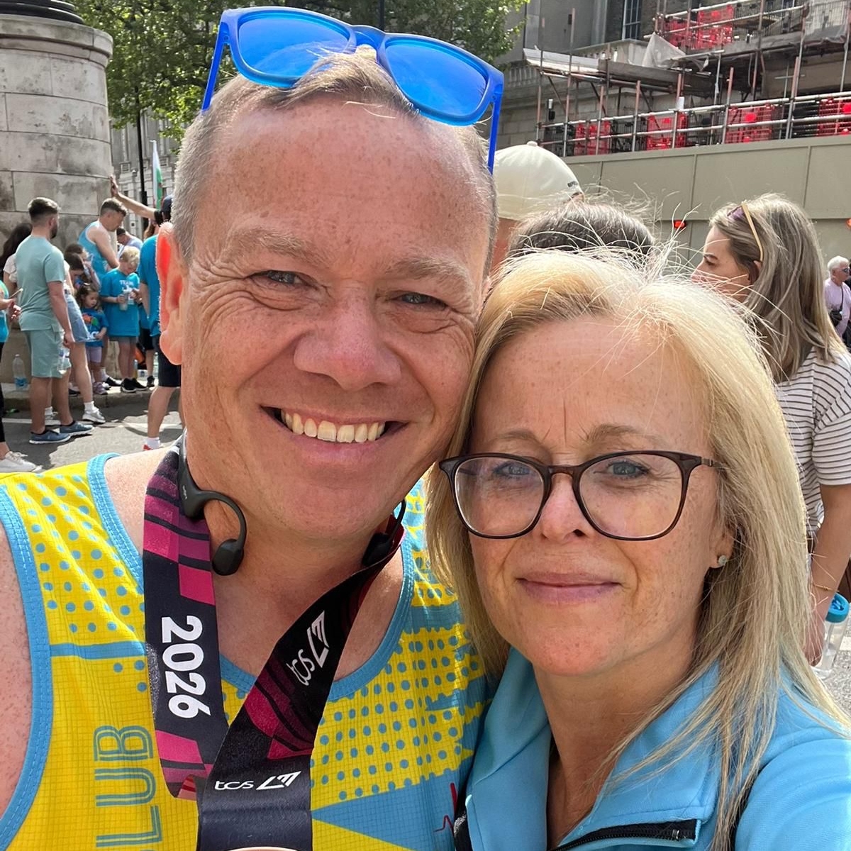 man proudly showing his medal alongside woman after running for Kids
