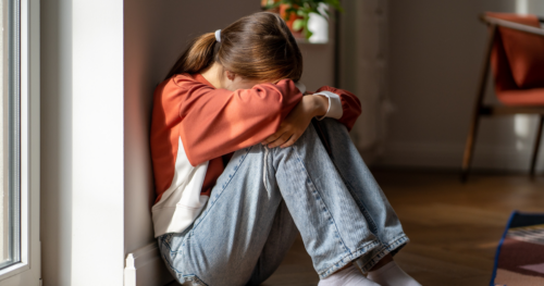 a teenage girl sits with her head in her hands